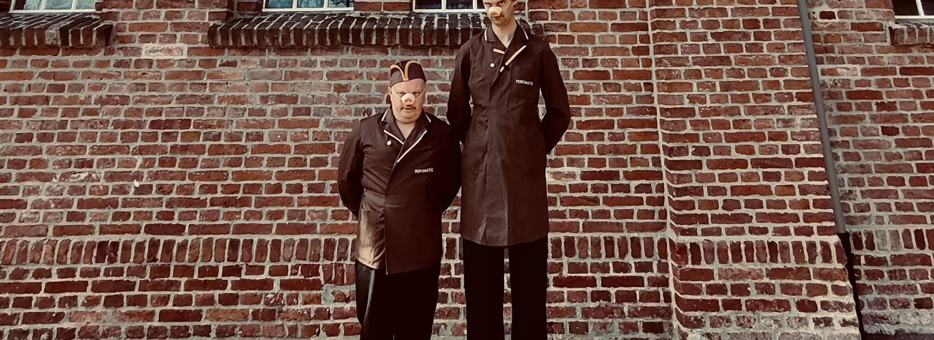 deux homems déguisés en bouchers cochon sont debout devant un mur de brique